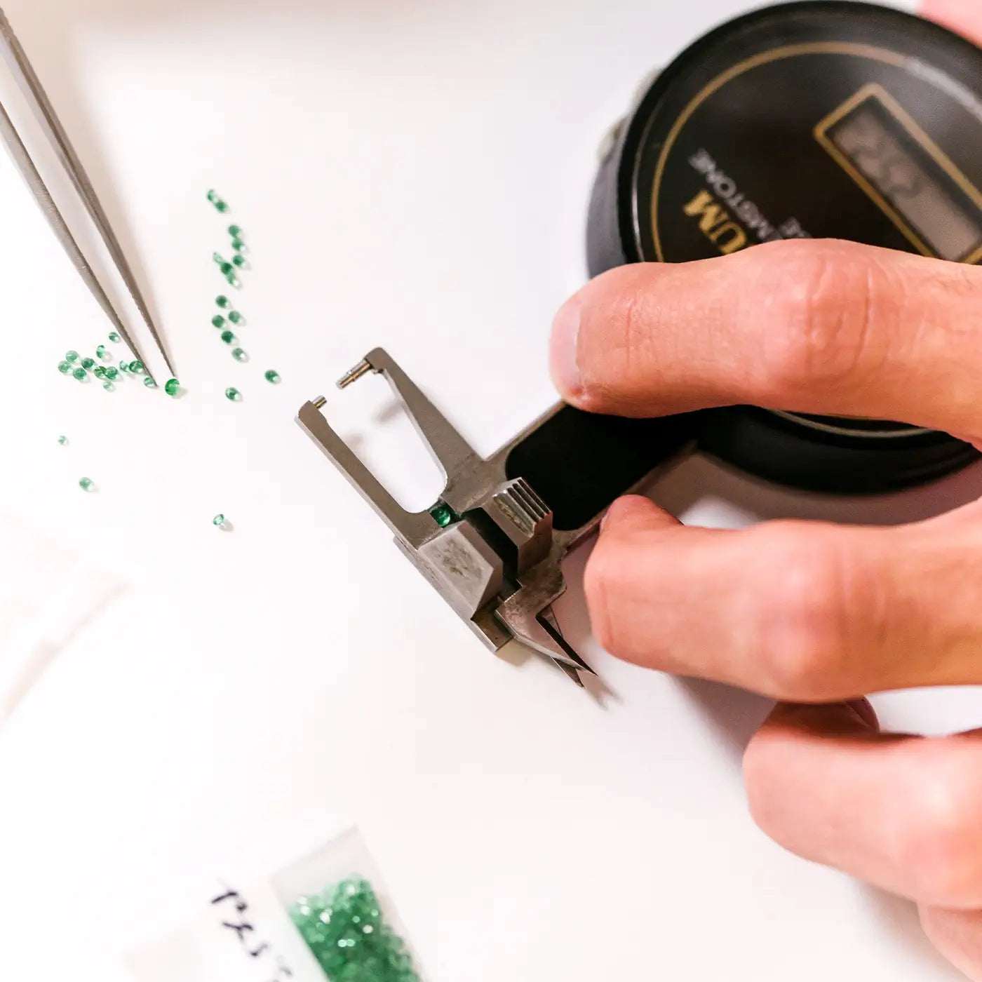 Gemmologist examining the cut of an emerald on a guédje to assess its proportions.
