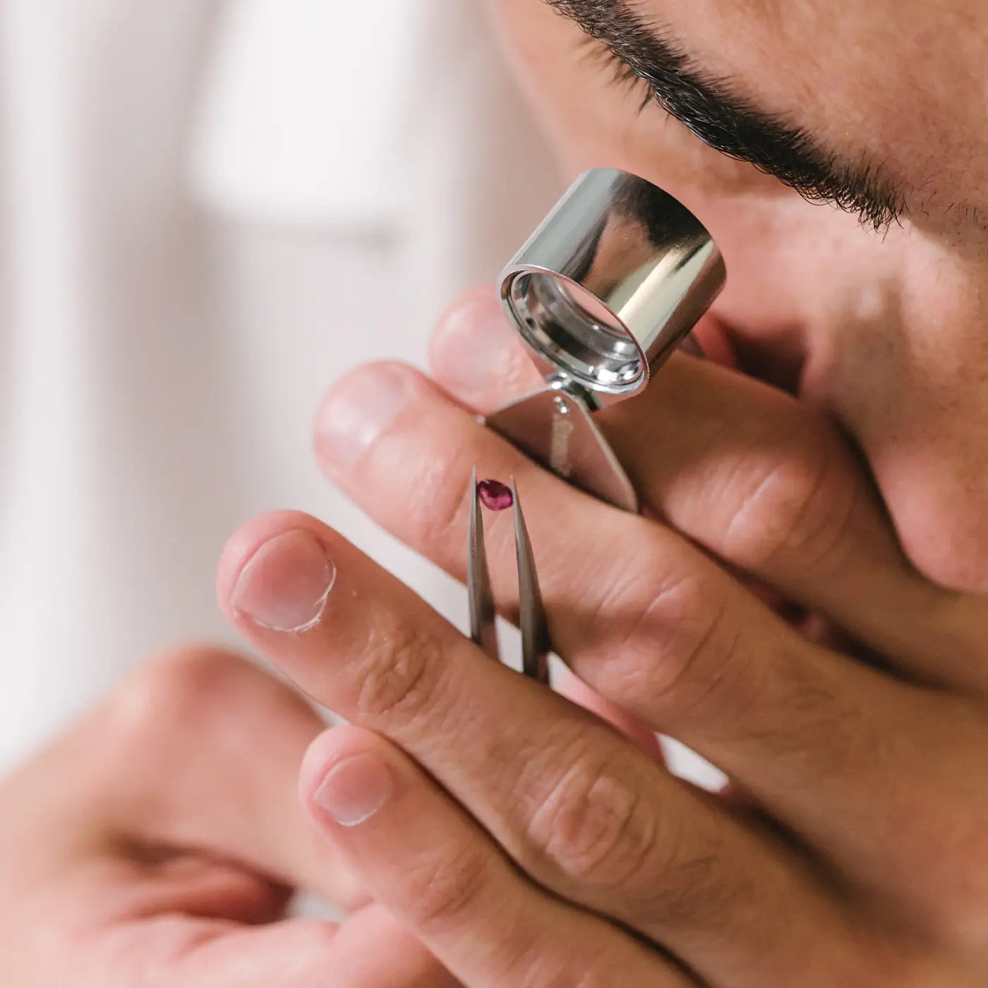 Gemmologist inspecting a natural ruby with a loupe to check its clarity.