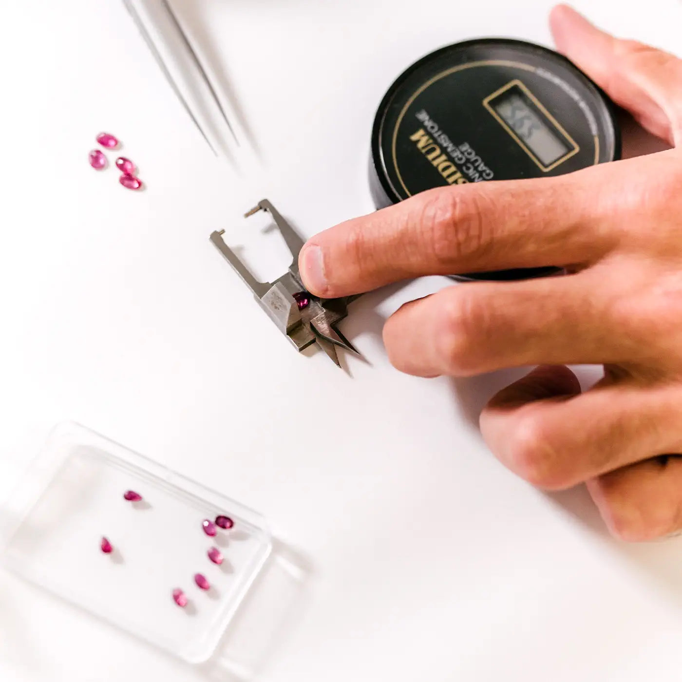 Gemmologist examining the cut of a ruby on a guédje to assess its proportions.