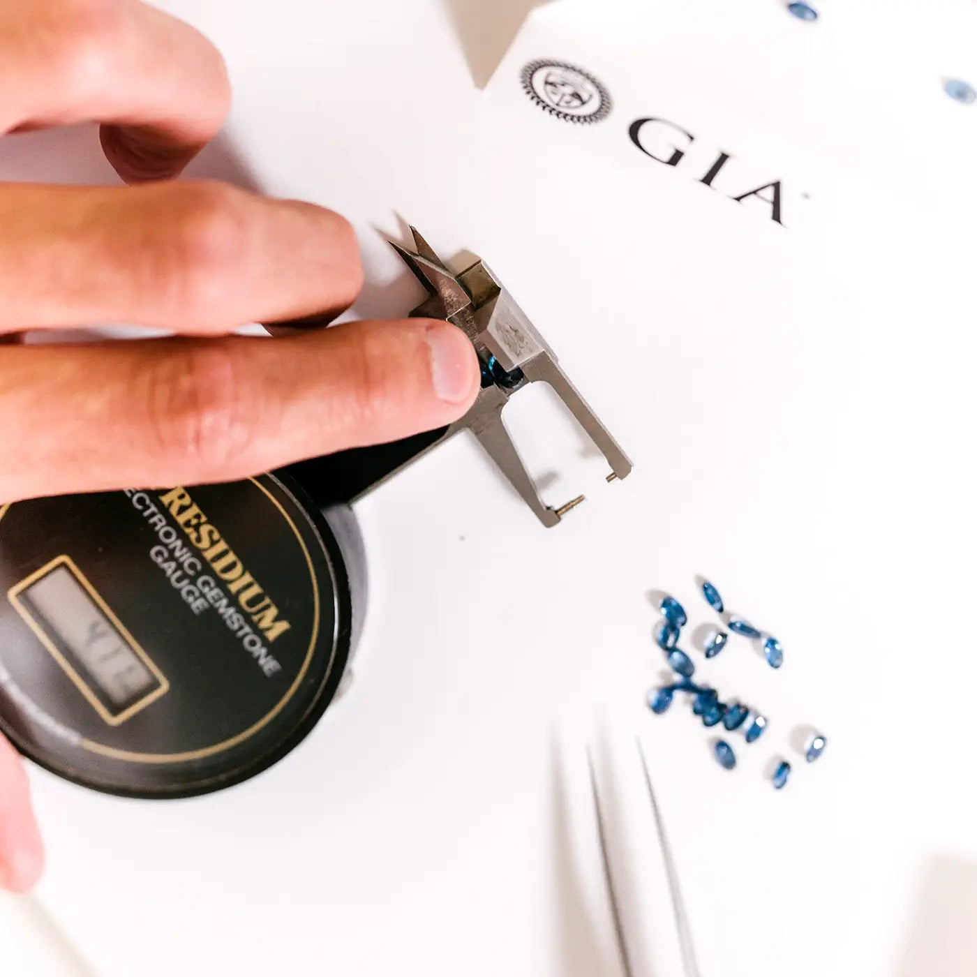 Gemmologist examining the cut of a blue sapphire on a guédje to assess its proportions.